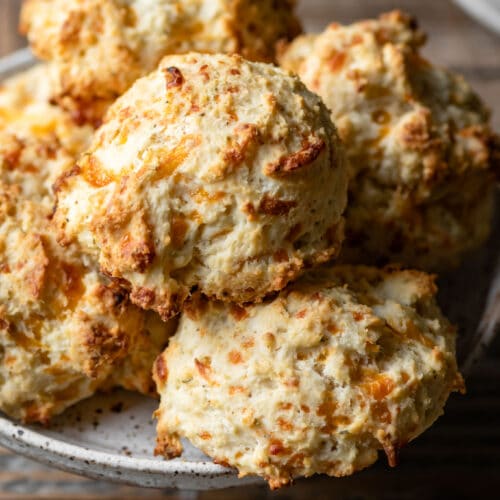 Close up of cheddar biscuits on a white plate.