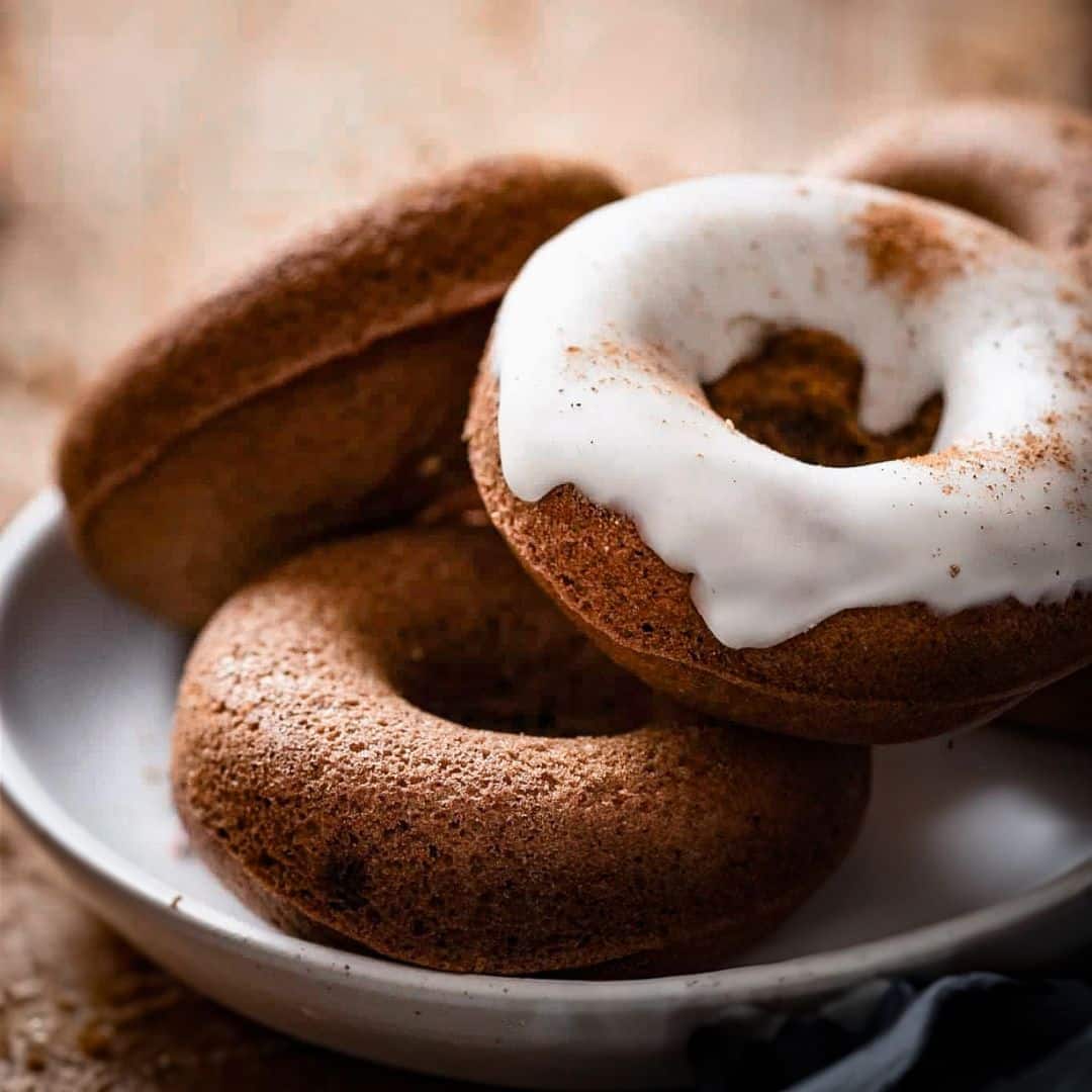 Stack of three donuts on a plate, one topped with vanilla icing.