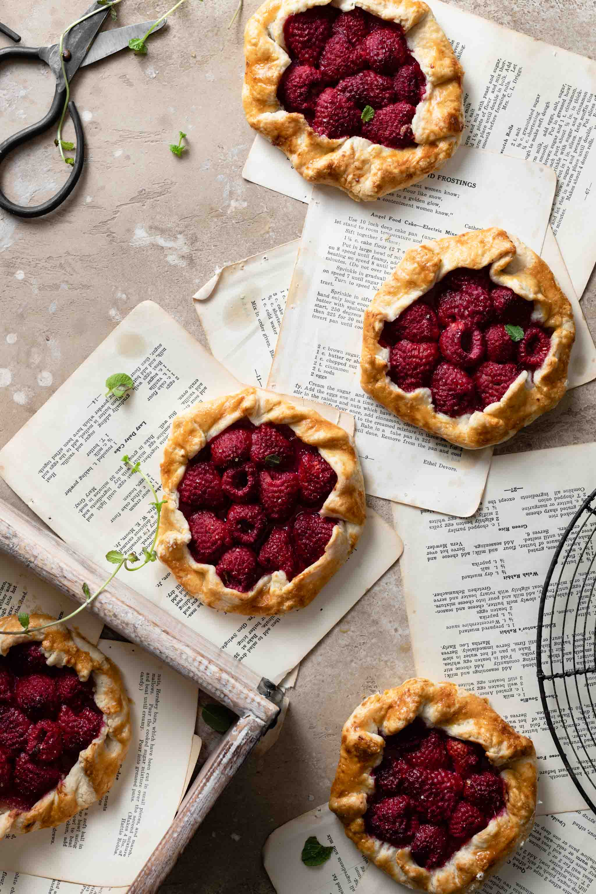 Raspberry hand pies on top of recipe pages.