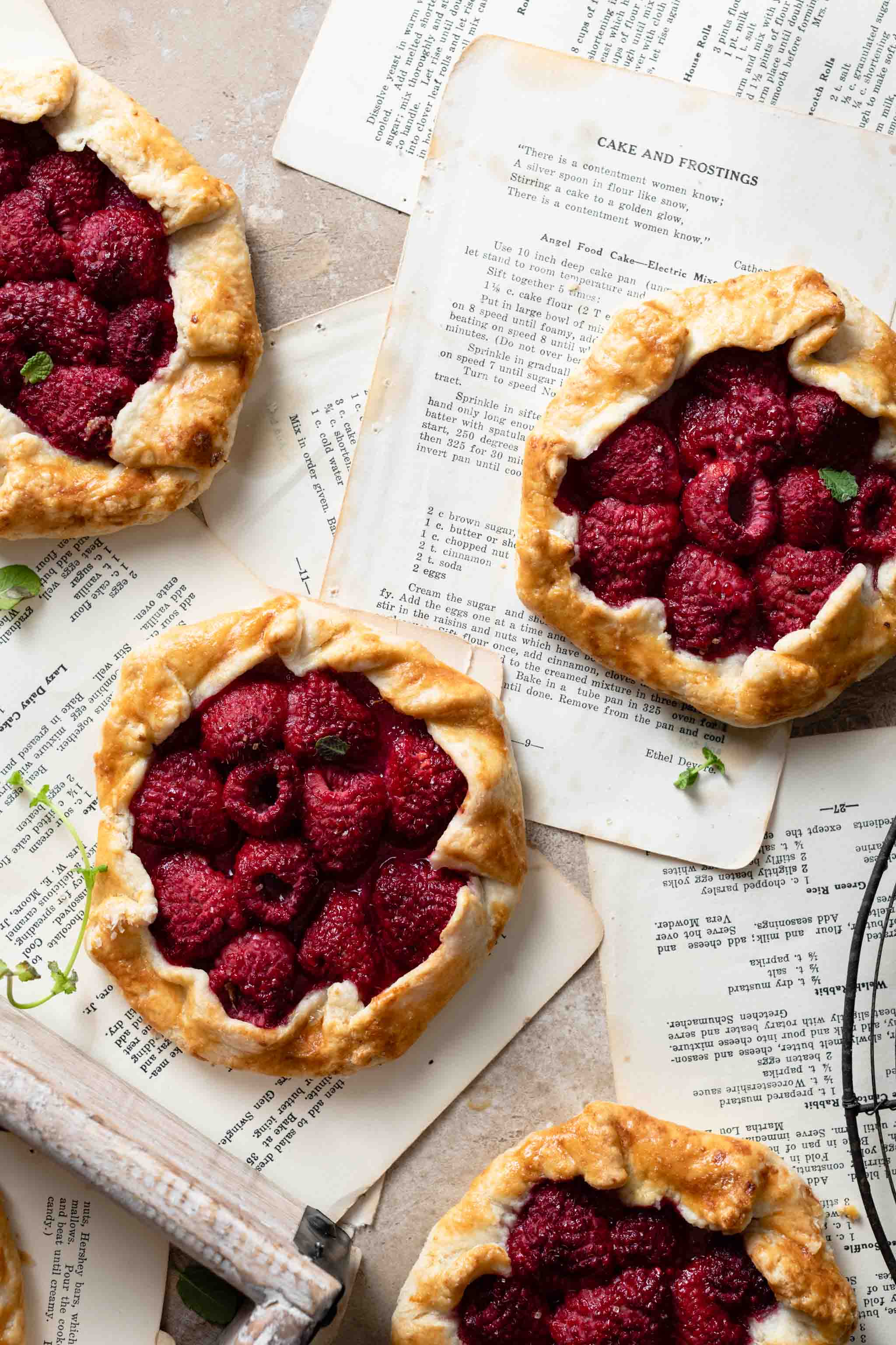 Small open faced raspberry pies on top of recipe pages.