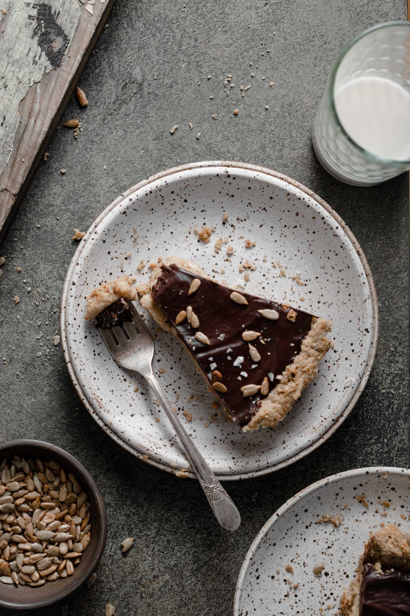 Slice of coconut chocolate tart with toasted sunflower seeds.