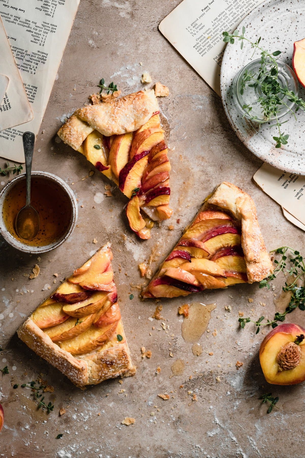 Three slices of a peach galette on a table top next to a bowl of honey.