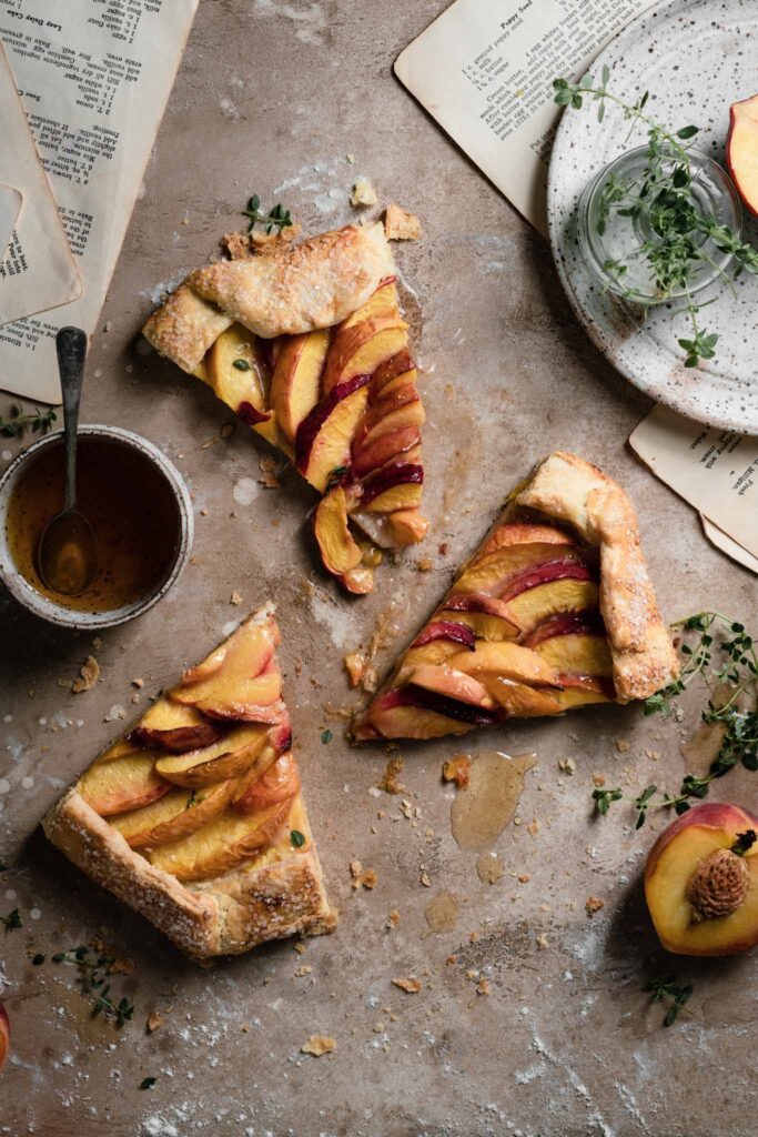 Pie slices of peach galette on table with drizzles of honey.