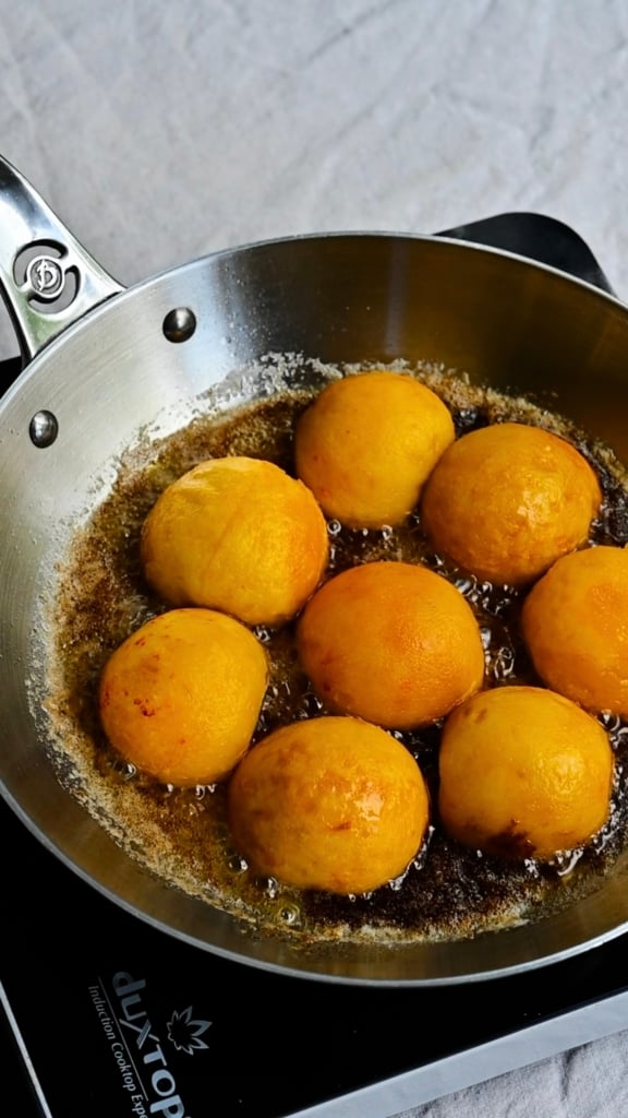 Yellow peach halves, face down in skillet of melted butter and brown sugar.