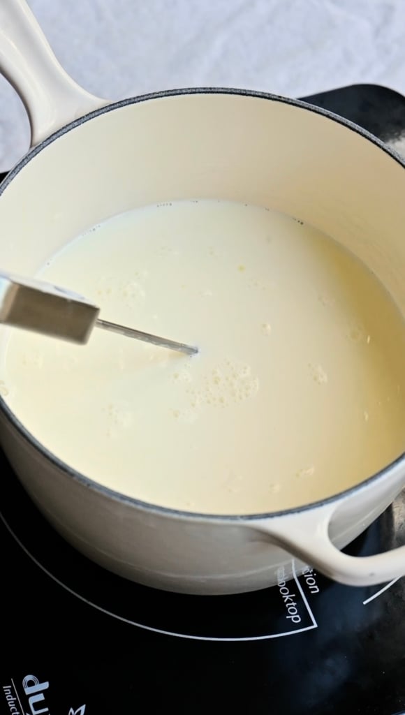 Thermometer inside a saucepan of cream.
