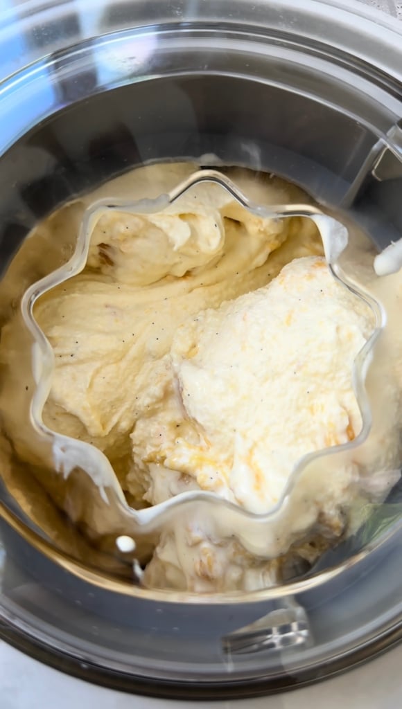 Overhead view of peach ice cream inside an ice cream maker.