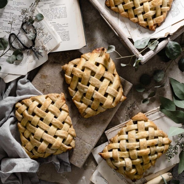 Four lattice apple hand pies on board.