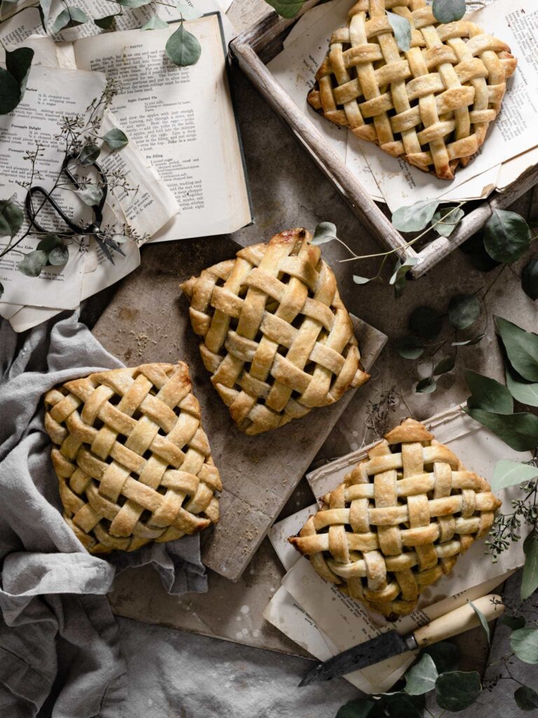 Four lattice apple hand pies on board.