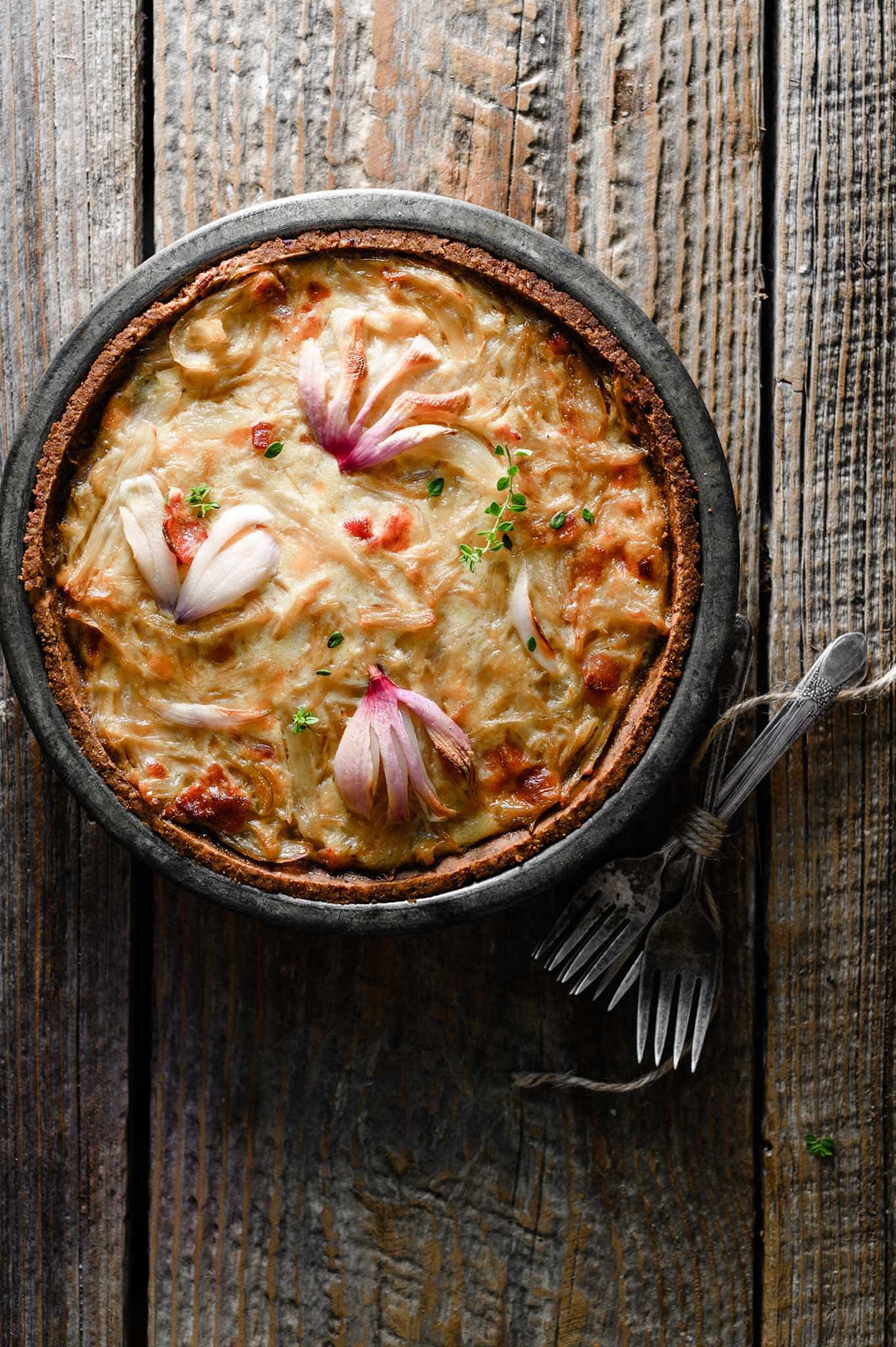 Onion tart in a pan with forks on table.