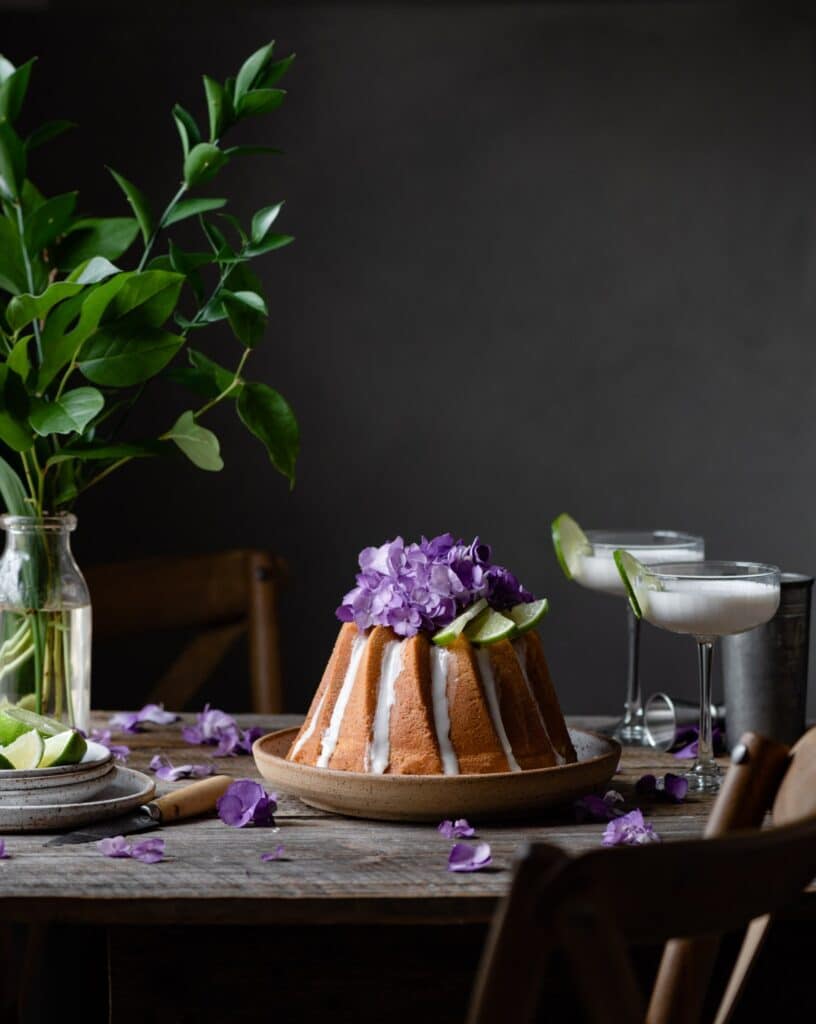 Key Lime Cake on table with flowers and cocktails.