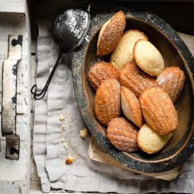 Plate in a wooden box filled with madeleine cookies.