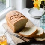 Sliced loaf of bread on table next to window.