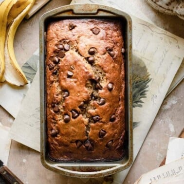 Loaf of banana bread topped with chocolate chips in a loaf pan.
