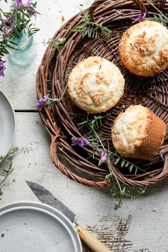 Above view of muffins topped with coconut in a brown basket.