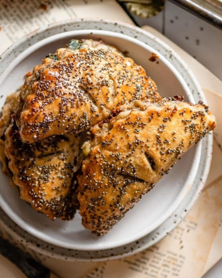 Three half moon shaped hand pies stacked on a plate.