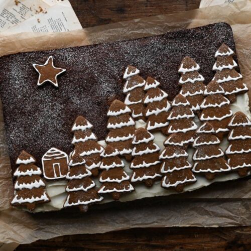 Rectangular gingerbread sheet cake topped with Christmas tree cookies.