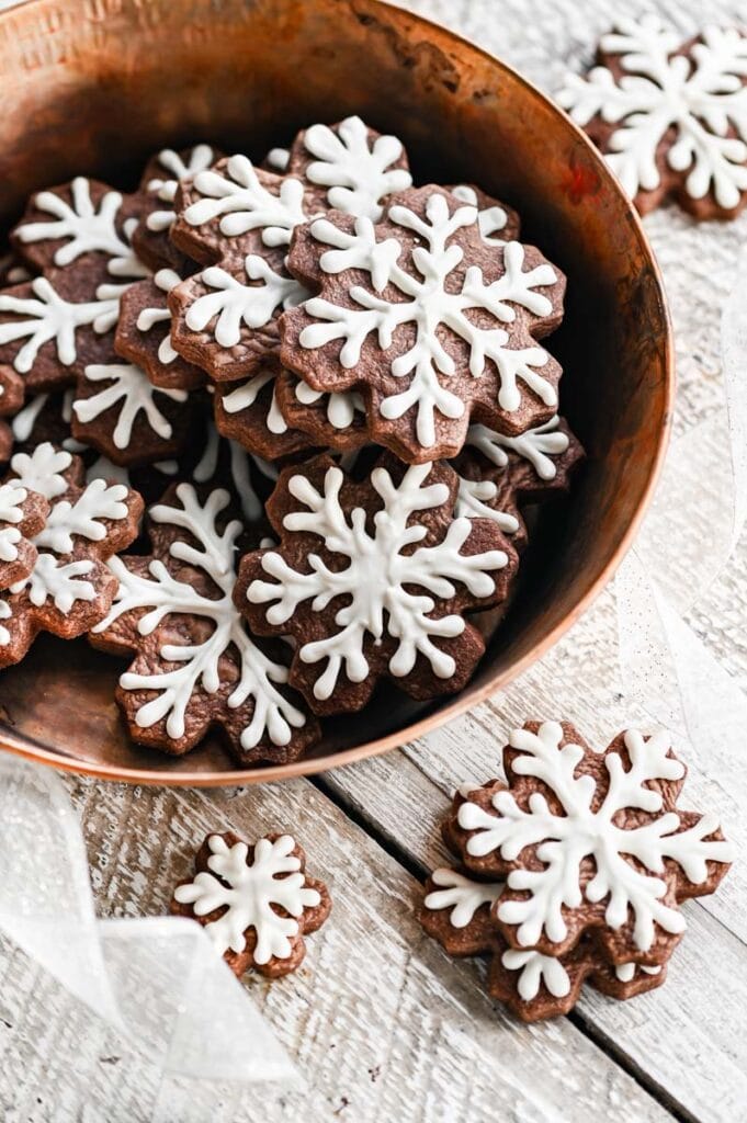 Copper bowl full of snowflake pipied chocolate sugar cookies.