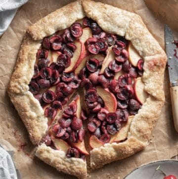 Closeup of a cherry and peach galette with a slice cut.