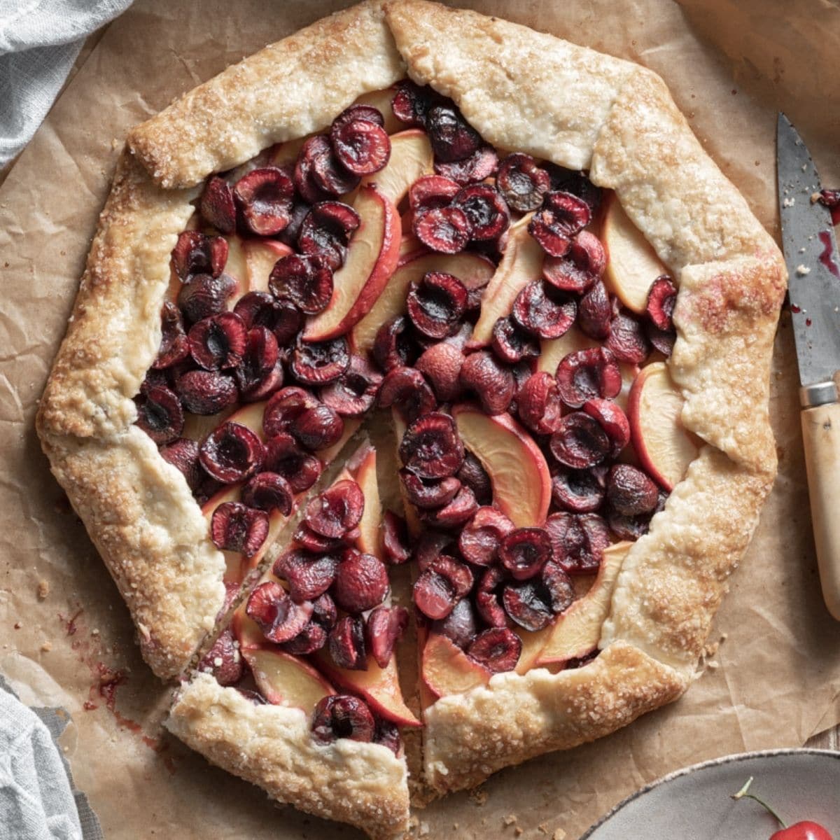 Closeup of a cherry and peach galette with a slice cut.