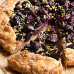 Dark cherry galette slice being pulled away with a pie server.