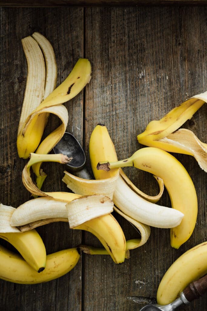 Several ripe bananas with peels on a wood table.