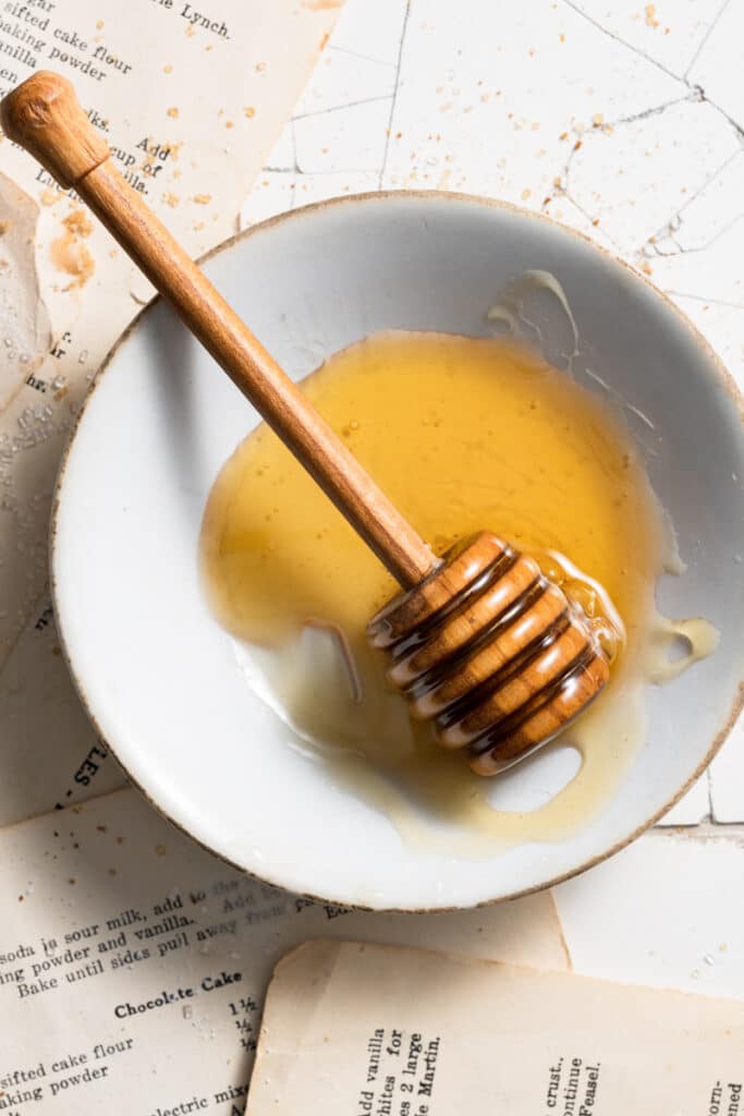 Small bowl of honey with a wooden honeycomb spoon.