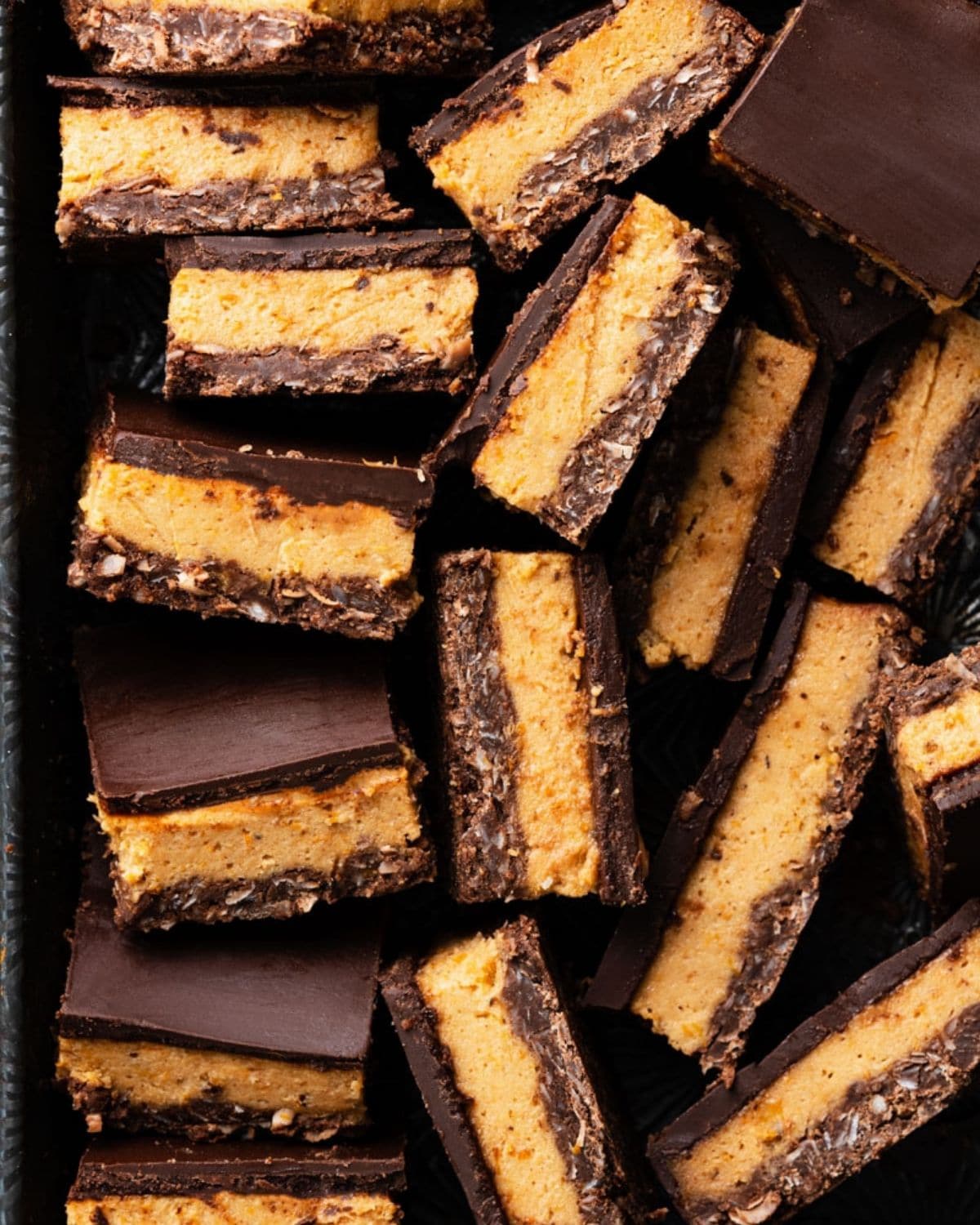 Close up of sliced chocolate and persimmon layer bars in a metal pan.