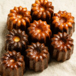 Overhead of baked caneles on a linen napkin.