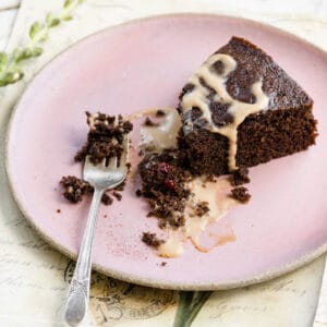 Slice of chocolate cake cut with a fork on a pink plate.