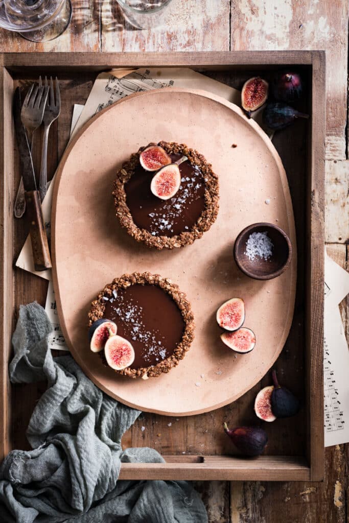 Two chocolate tarts on a peach plate inside a wooden box.
