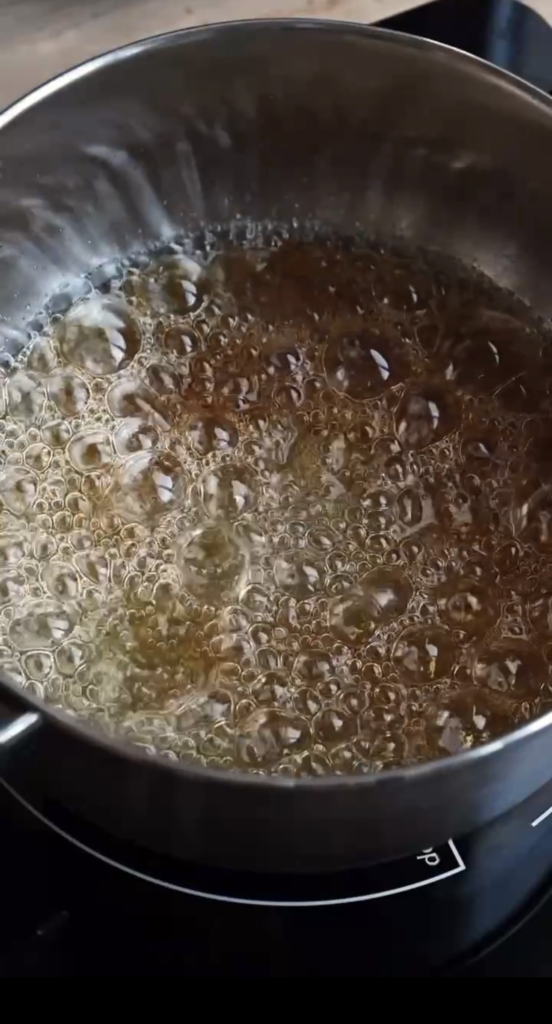 Pot of boiling sugar turning caramel in color.