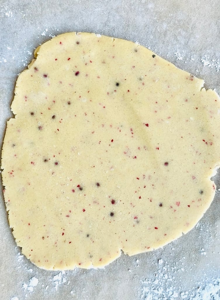 Linzer cookie dough rolled out on parchment paper.