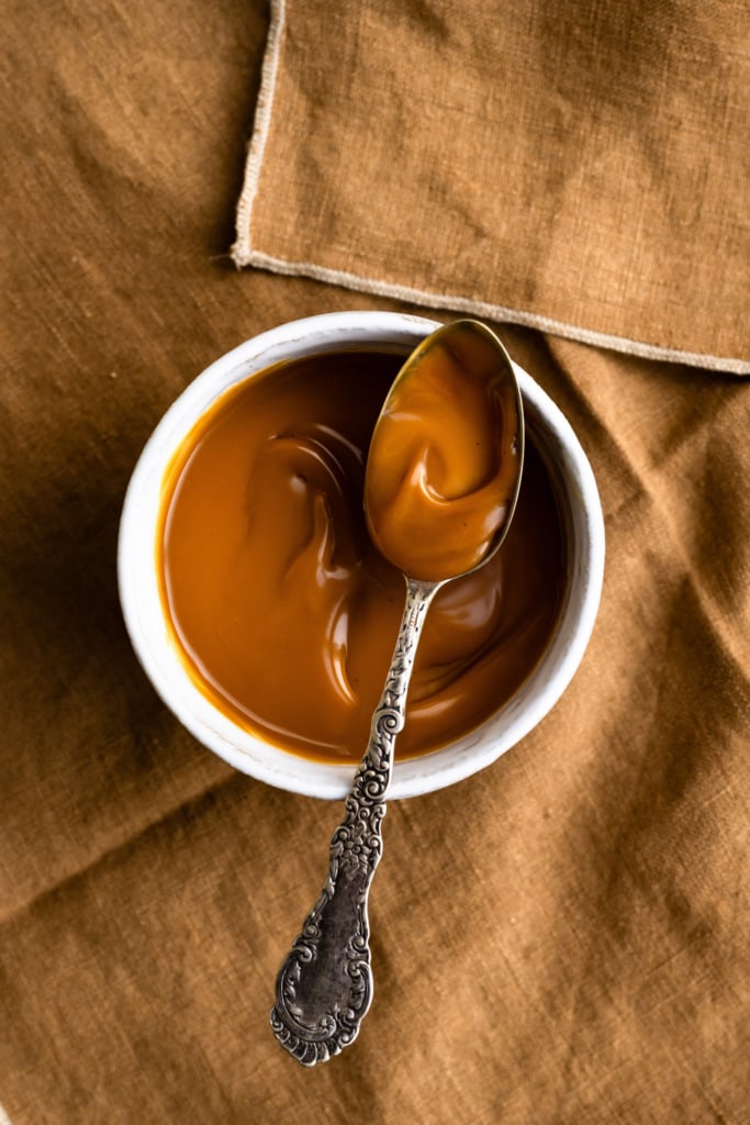 Overhead bowl of homemade caramel sauce with a spoon.