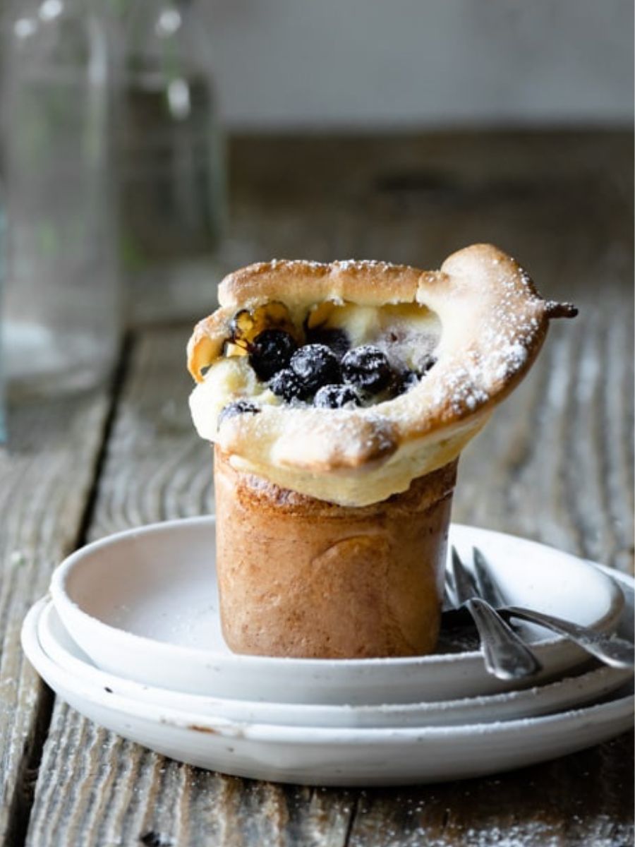 Blueberry popover on a stack of plates with two forks.