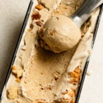 Overhead of a scoop of coffee ice cream with croissant chunks in a tub.