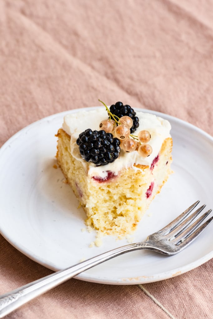 Slice of cake topped with whipped cream and berries on a plate.