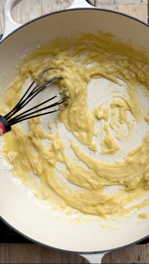 Flour and butter roux being stirred in a pan.