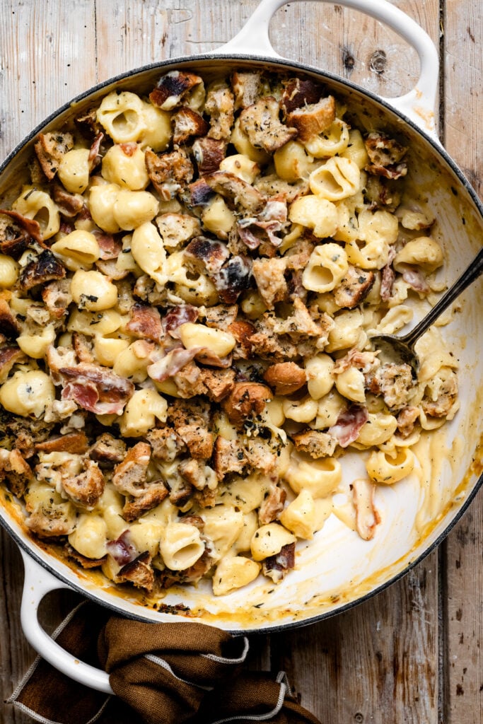 Round casserole dish filled with baked mac and cheese that's topped with croutons.
