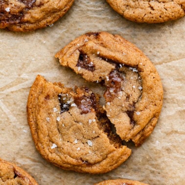 Closeup of a toffee cookie broken in half on a piece of parchment paper.