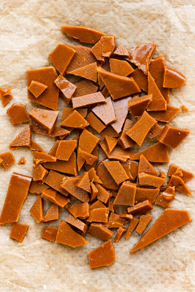 Homemade toffee chopped into pieces on a silicone mat.