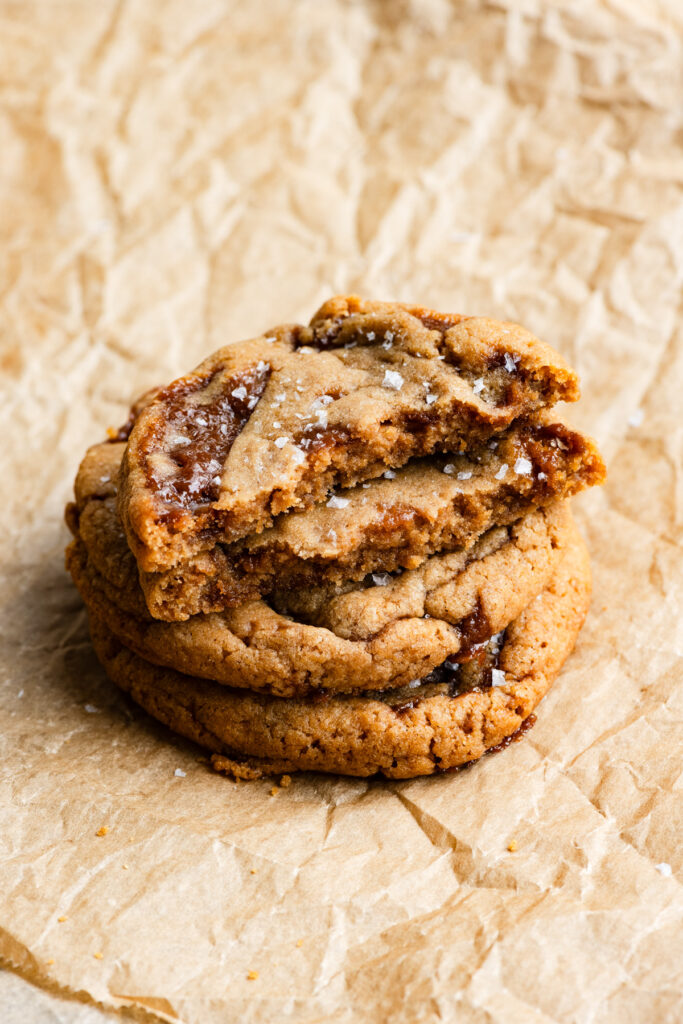 Stack of cookies filled with toffee and the top cookie is broken in half.