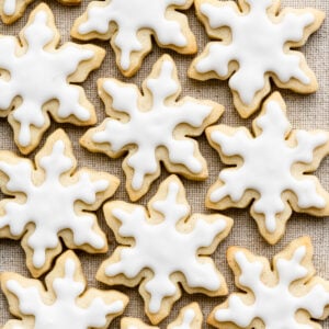 Overhead of snowflake shaped cookies with white icing on a cloth.