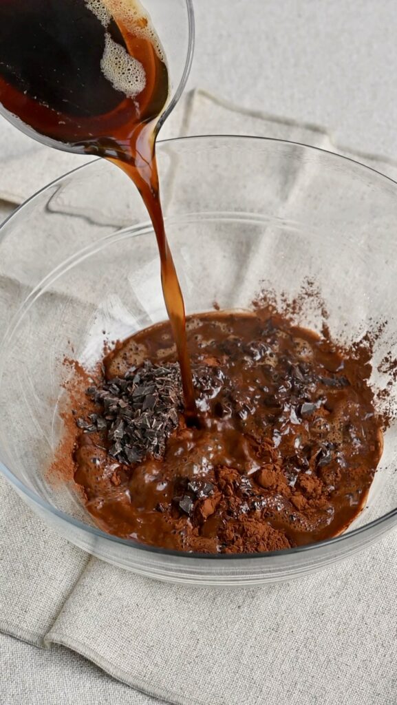 Hot coffee being poured into a bowl of chocolate and cocoa powder.