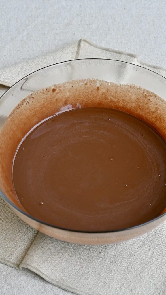 Thick and shiny chocolate cake batter in a mixing bowl.