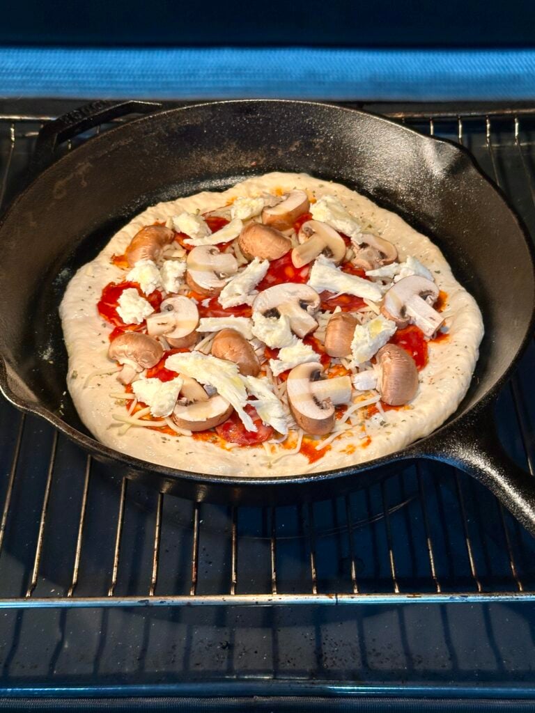 Pan pizza baking on the lowest rack of an oven.