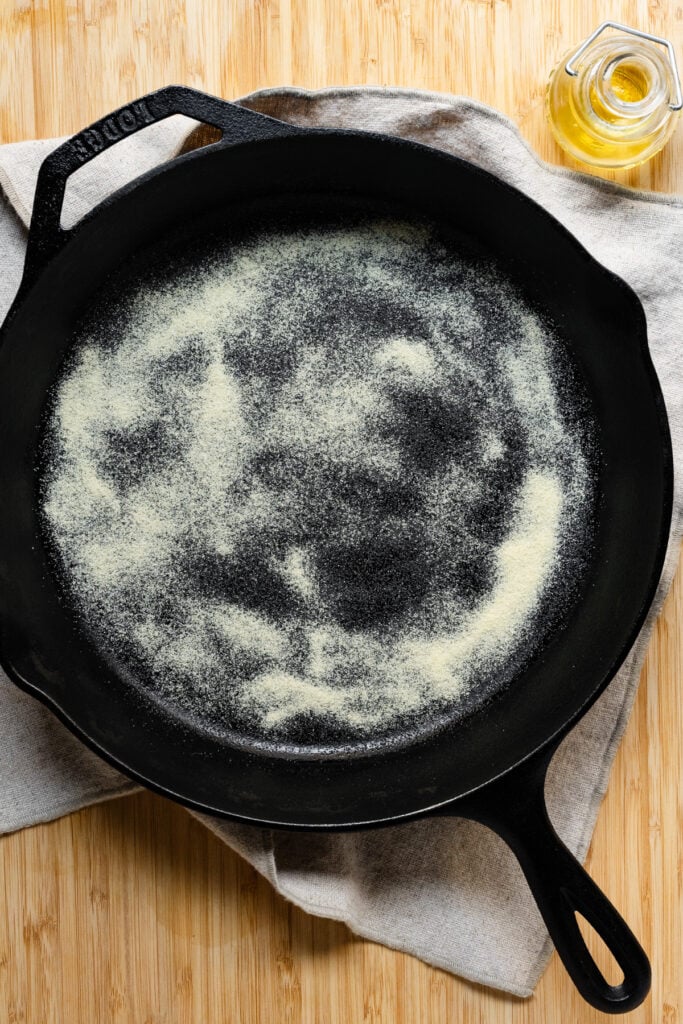 Overhead of a cast iron skillet coated with oil and semolina flour.