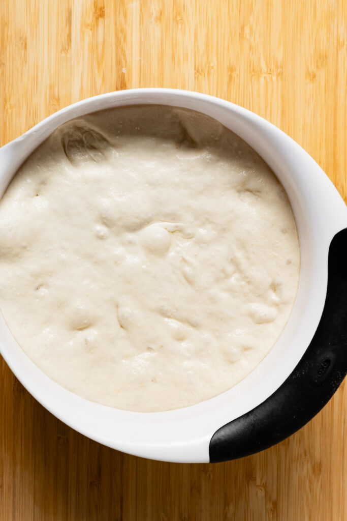 Overhead of pizza dough in a mixing bowl.