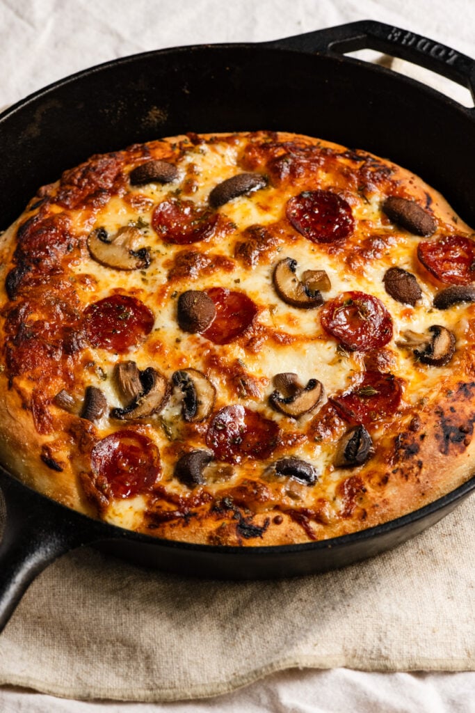 Baked pepperoni and mushroom pan pizza in a cast iron skillet.
