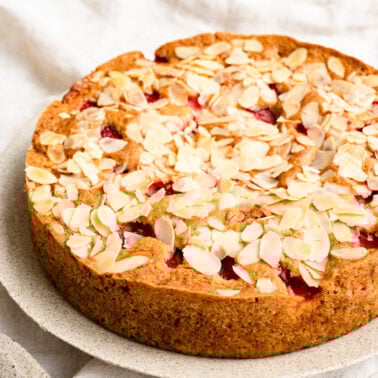 Strawberry cake topped with toasted almond slices on a plate.