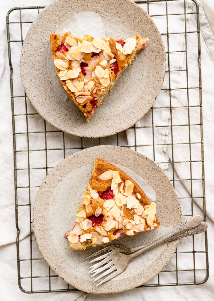 Overhead of two strawberry cake slices on plates with forks.
